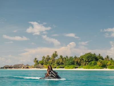 Person auf Jetski mit tropischer Insel und Strand im Hintergrund bei klarem Himmel