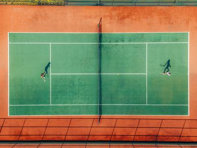 Vogelperspektive eines Tennisplatzes mit zwei Spielern beim Spiel.