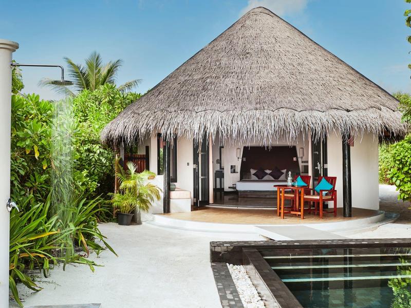 Bungalow de baño con techo de paja, muebles de madera y piscina privada en entorno tropical.