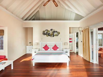 Helles Schlafzimmer mit Holzboden, Doppelbett und roter Dekoration.