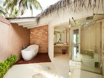 Moderne Hotelbadezimmer mit freistehender Badewanne und Glasdusche im tropischen Ambiente.