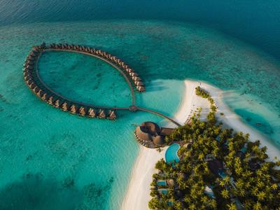 Luxuriöse Überwasser-Bungalows in herzförmiger Anordnung auf türkisfarbenem Wasser.