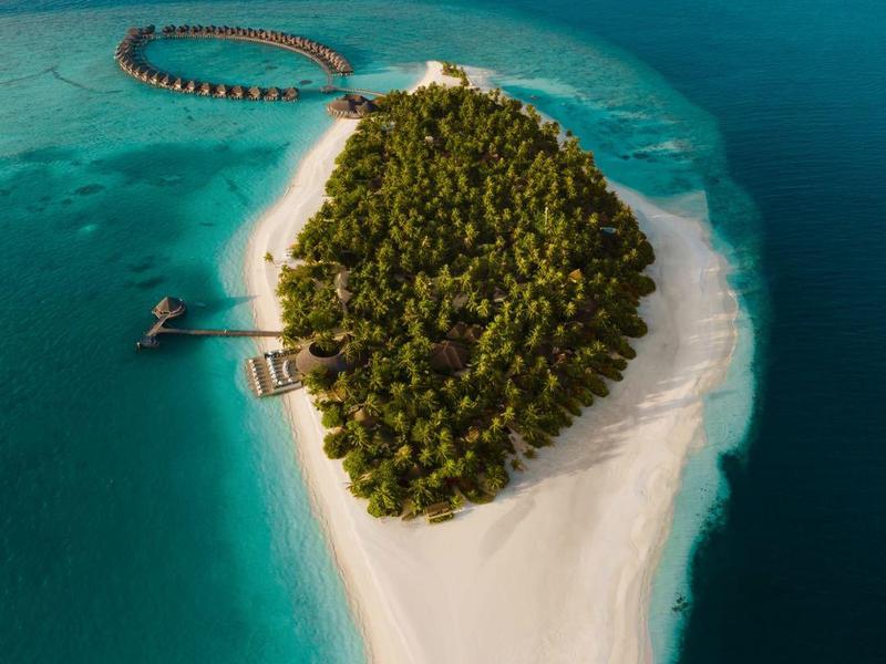 Isola tropicale con spiaggia, acqua blu chiara e moli di legno nell'oceano.