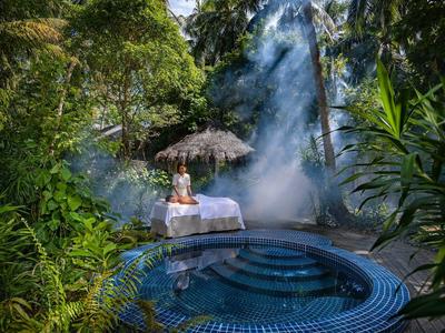 Osoba odpoczywa na leżaku przy mistycznym jacuzzi w gęstej tropikalnej dżungli.