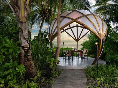 Przytulny pawilon z miejscami do siedzenia w tropikalnym ogrodzie o zachodzie słońca.