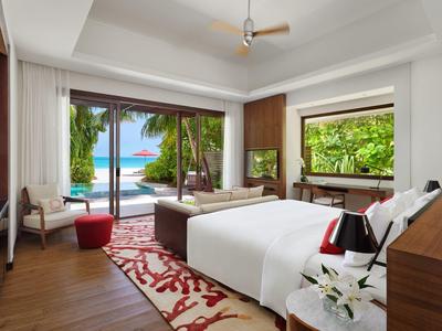 Jasny pokój hotelowy z podwójnym łóżkiem, widokiem na basen i morze przez duże okna.