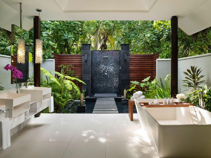 Otwarta łazienka z wolnostojącą wanną i prysznicem na zewnątrz w tropikalnym otoczeniu.