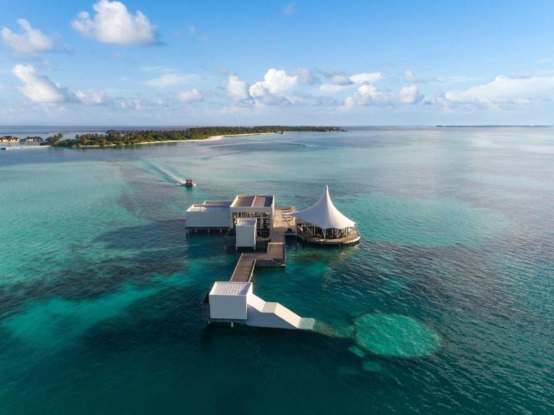 Luksusowe domki nad wodą w przejrzystej turkusowej wodzie pod niebieskim niebem.