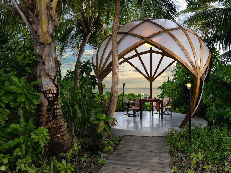 Przytulny pawilon z miejscami do siedzenia w tropikalnym ogrodzie o zachodzie słońca.