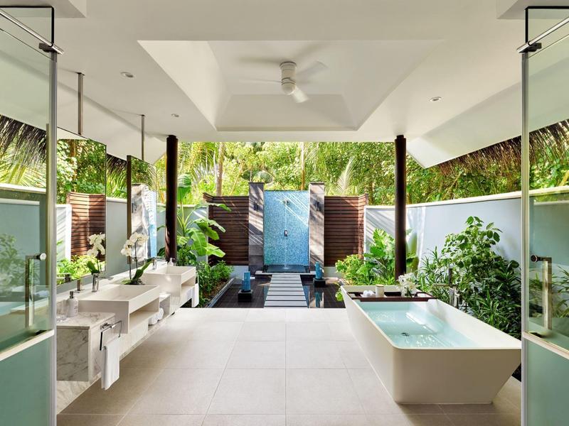 Otwarta łazienka z wolnostojącą wanną, podwójną umywalką i widokiem na ogród z basenem.