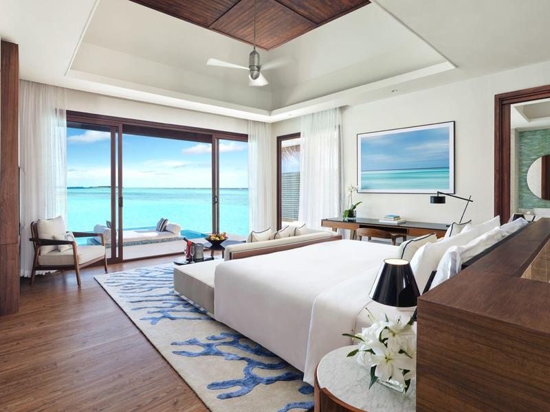 Nowoczesny pokój hotelowy z łóżkiem, miejscem do siedzenia i widokiem na morze przez duże okna.