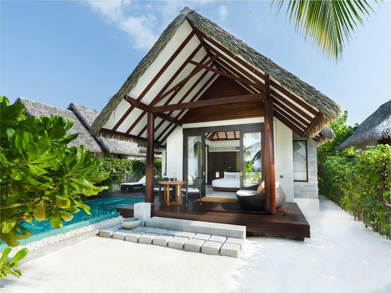 Otwarty taras z podwójnym łóżkiem w tropikalnym bungalowie przy basenie i białym piasku.