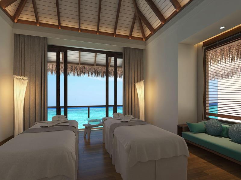 Luksusowy pokój spa z dwoma stołami do masażu i widokiem na morze przez duże okna.