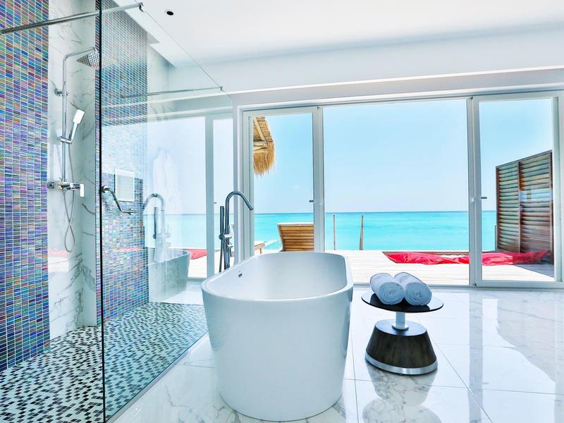 Moderner heller Badezimmer mit freistehender Badewanne und Blick auf das Meer.