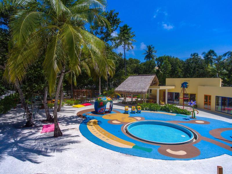 Bunter Kinderpool mit Liegen und Palmen im Freien an sonnigem Tag.