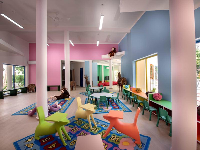 Bunte Kinderspielecke mit Spielzeugstühlen und Arbeitsplätzen in einem modernen Raum.