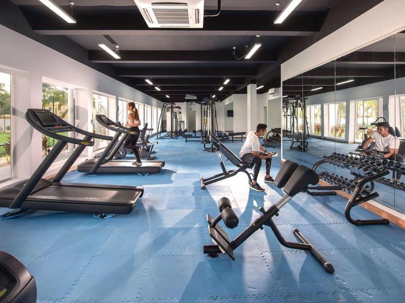 Moderner Fitnessraum mit Laufbändern, Gewichten und blauen Bodenflächen.