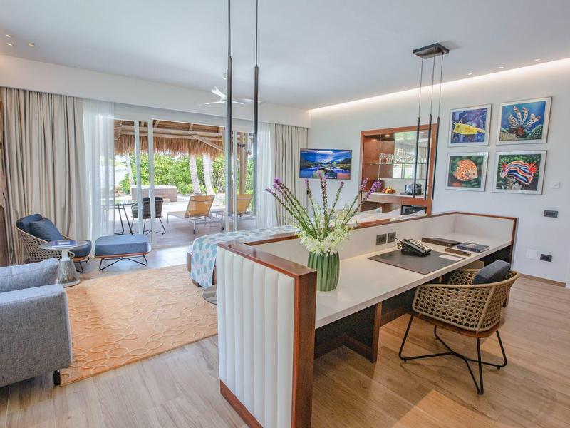 Moderner Hotelzimmerbereich mit Sitzgelegenheiten, Schreibtisch und Zugang zur Terrasse mit Sitzbank.