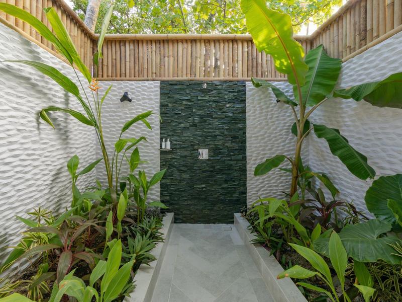 Moderne hotel tuin met weelderige groene planten en een donkere waterpartij aan de muur.