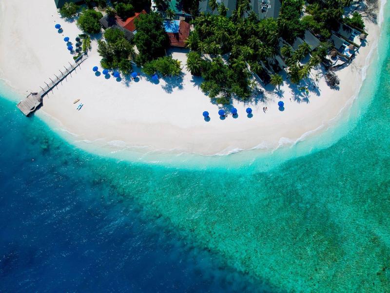 Luchtfoto van een tropisch eiland met wit zandstrand en helder blauw water.