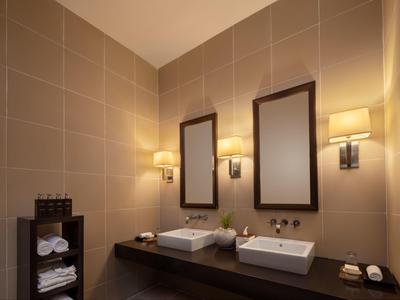 Modernes Badezimmer mit zwei rechteckigen Spiegeln, weißen Waschbecken und warmem Wandlicht.