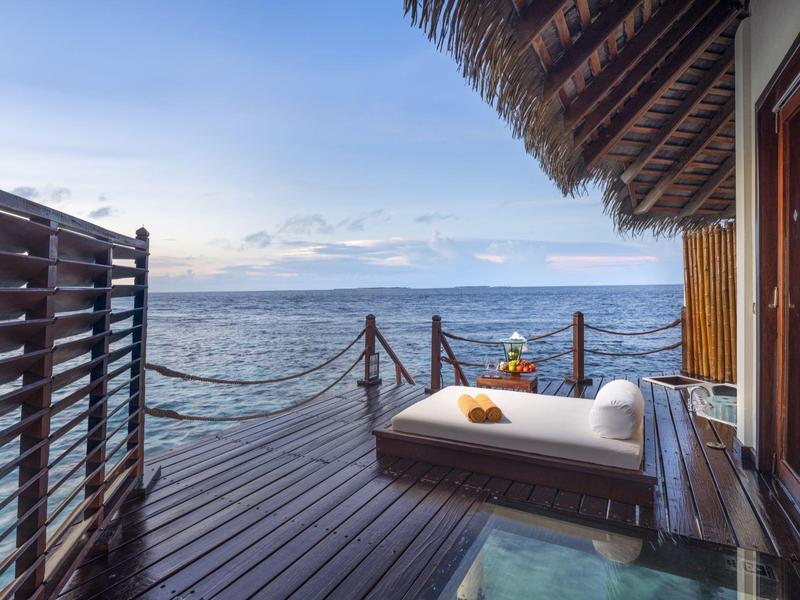 Terras met ligstoel met uitzicht op de oceaan bij zonsondergang.