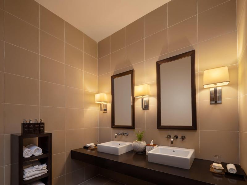 Moderne badkamer met twee wastafels, spiegels en warme wandlampen.