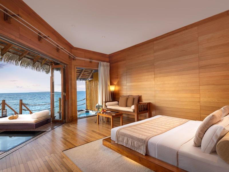 Moderne kamer met houten muren, groot bed, terras en zeezicht.