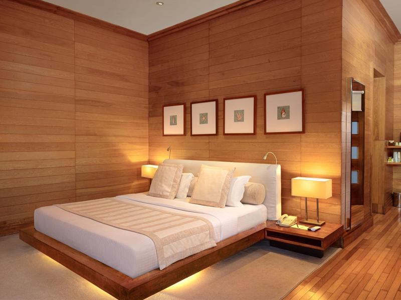 Moderne slaapkamer met houten muren, tweepersoonsbed en warm licht.