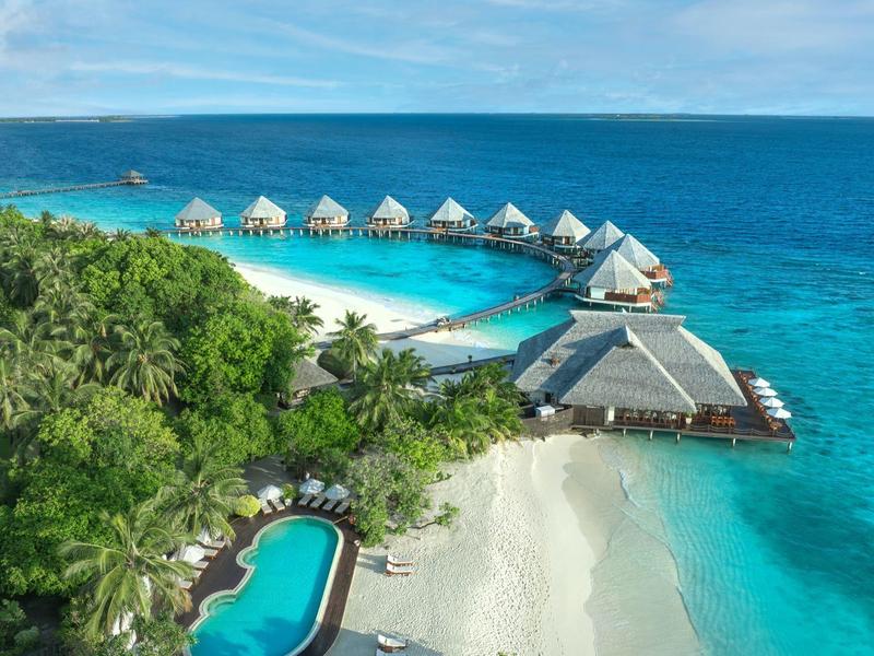 Luxe bungalows op het water en zwembad aan een tropisch strand met kristalhelder water.