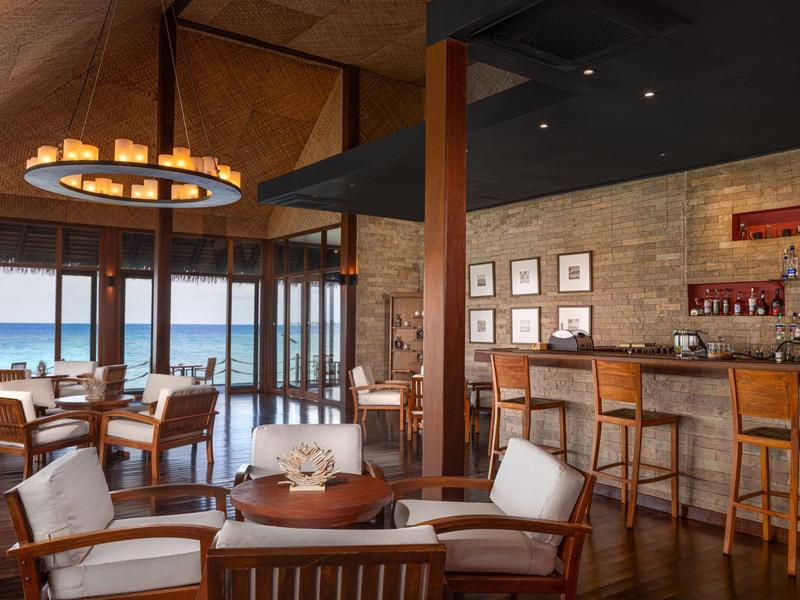 Gezellige hotelbar met houten meubels, stoelen en zeezicht door grote ramen.