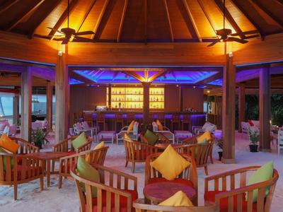 Bar accogliente in hotel con mobili in legno, divani e illuminazione calda e colorata.