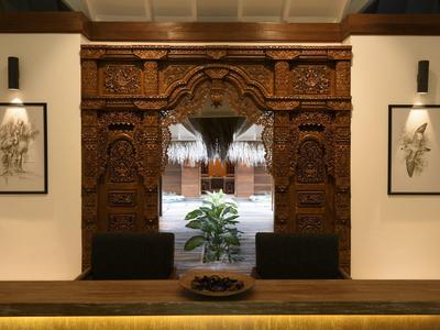 Intagliatura in legno raffinata incornicia un passaggio verso un cortile interno con piante.