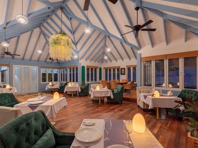 Accogliente sala da pranzo dell'hotel con alti soffitti a volta e tavoli elegantemente apparecchiati alla sera.