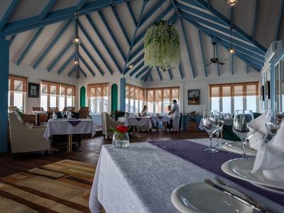 Ristorante elegante con soffitti alti, travi di legno blu e tavoli apparecchiati.