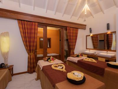 Accogliente stanza spa con due lettini da massaggio, colori caldi e decorazioni.