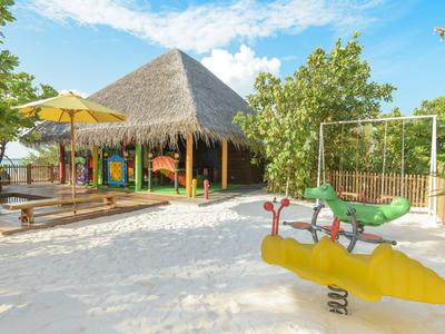 Parco giochi sabbioso dell'hotel con giochi a molla e padiglione con tetto di paglia