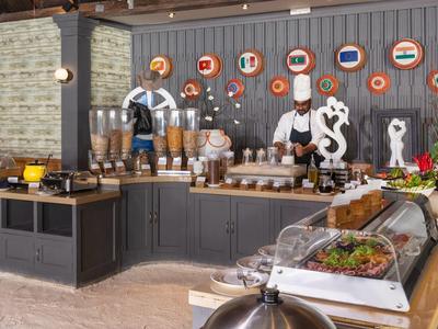 Area buffet con vari cibi e bevande, decorata con bandiere internazionali.