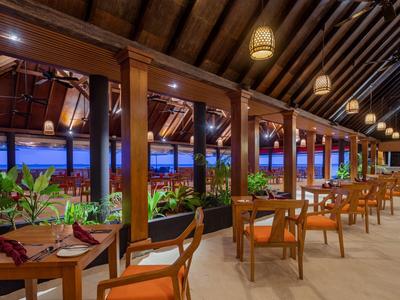 Ristorante aperto con mobili in legno e piante che creano un'atmosfera rilassata al crepuscolo.