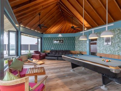 Großer, offener Aufenthaltsraum mit Billardtisch, Sofas und Panoramafenstern mit Bergblick.