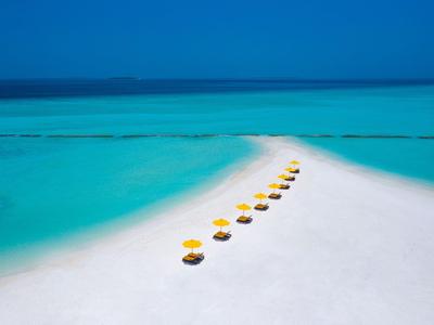Spiaggia di sabbia bianca con ombrelloni gialli in acqua turchese.