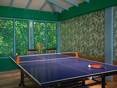 Innenraum mit blauem Tischtennistisch und dekorativen grünen Wänden.