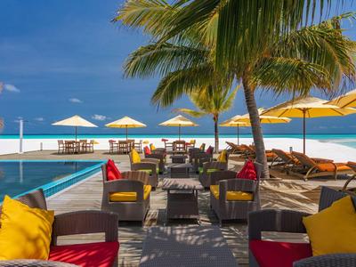 Elegante Strandlounge mit Palmen, bunter Polsterung, Sonnenschirmen und blauem Himmel.