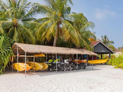 Gelbe Kajaks unter einem Strohdach auf einem weißen Sandstrand mit Palmen im Hintergrund.