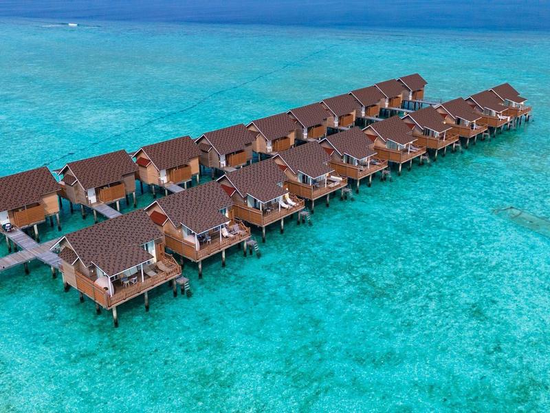 File di ville sull'acqua con tetti rossi sopra acqua turchese.