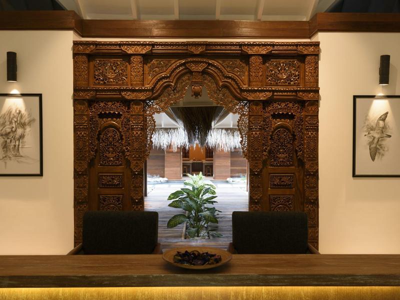 Intagliatura in legno raffinata incornicia un passaggio verso un cortile interno con piante.