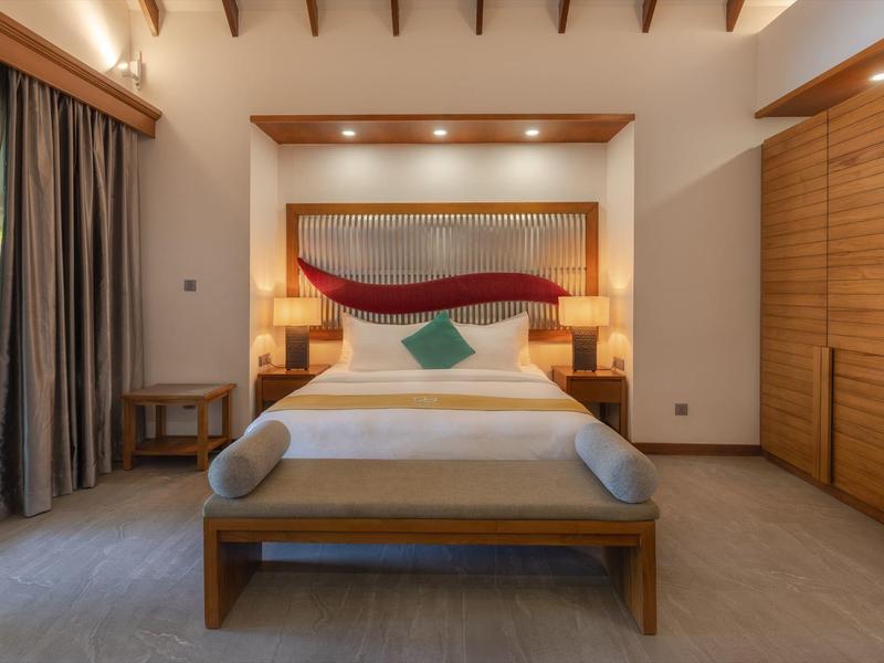 Camera d'hotel moderna con mobili in legno e letto accogliente in toni caldi.