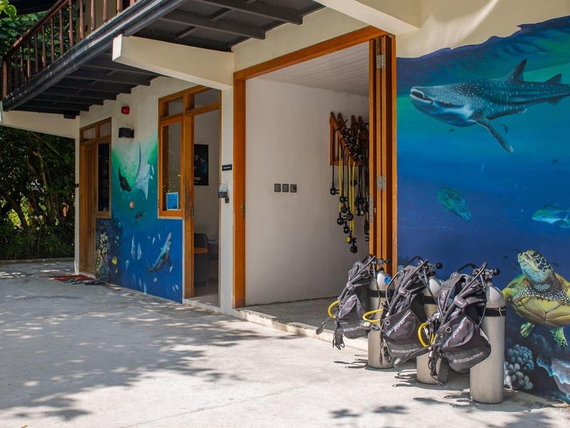 Ingresso di un edificio con murales di creature marine e diverse borse da golf davanti.