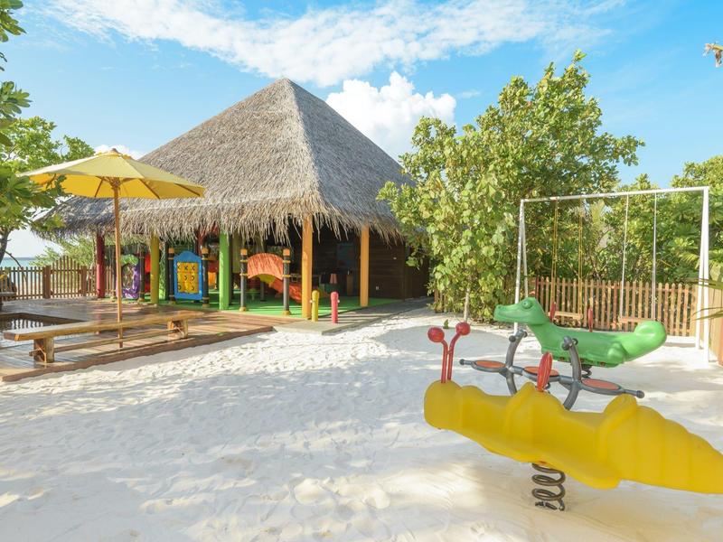 Parco giochi sabbioso dell'hotel con giochi a molla e padiglione con tetto di paglia