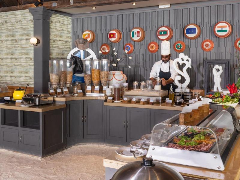 Area buffet con vari cibi e bevande, decorata con bandiere internazionali.